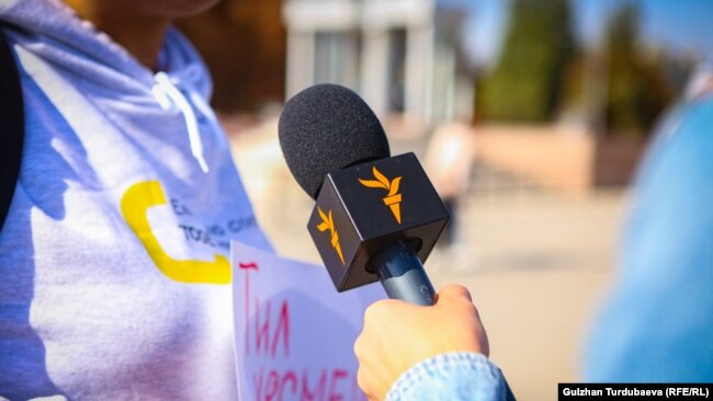 A demonstrator marching in support of independent media is interviewed and speaks into an RFE/RL microphone.