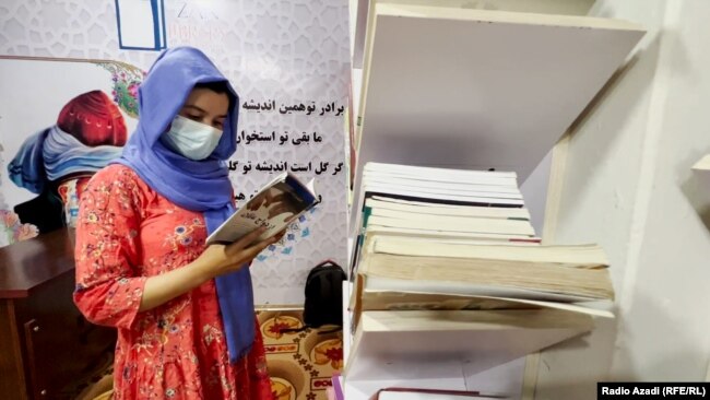 Deprived of education, a woman holds a book at Female-Only Kabul Library.