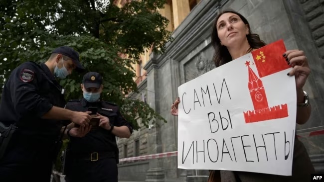 A journalist holds a placard which reads "Foreign agents yourself" during an August 21, 2021 solidarity protest for colleagues designated as "foreign agents," near the headquarters of Russia's Federal Security Service in Moscow.