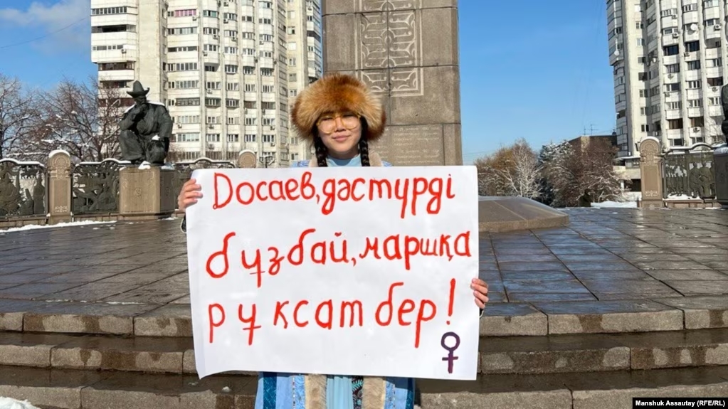 Activist Liya Bergen stands by the monument to independence with a sign addressing the mayor: “Dosaev, don’t break tradition, allow the march!” in Almaty, Kazakhstan on Feb. 2, 2024. Manshuk Assautay (RFE/RL).