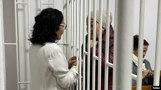 Activist Perizat Suranova and her mother speak between prison cell bars.