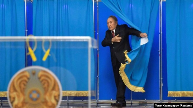 Former President Nursultan Nazarbayev walks out of a voting booth during presidential elections in Astana.