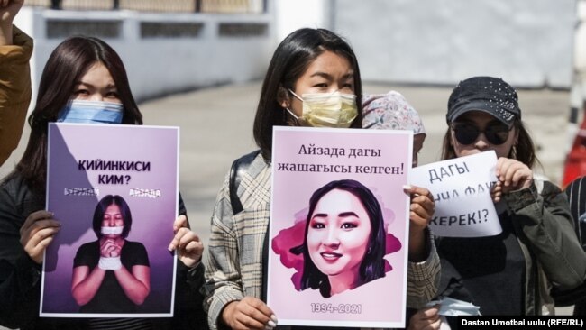 Three women hold posters protesting the death of Aizada Kanatbekova.