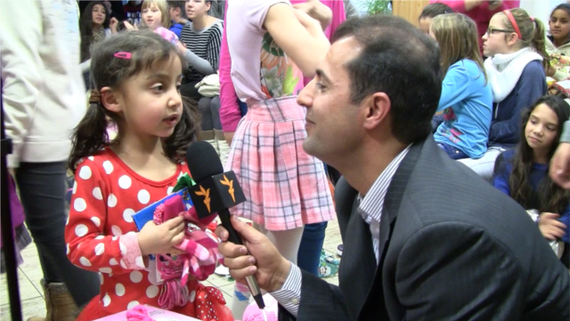 Radio Mashaal reporter Ahmad Shah Azami holds a microphone up to a young girl